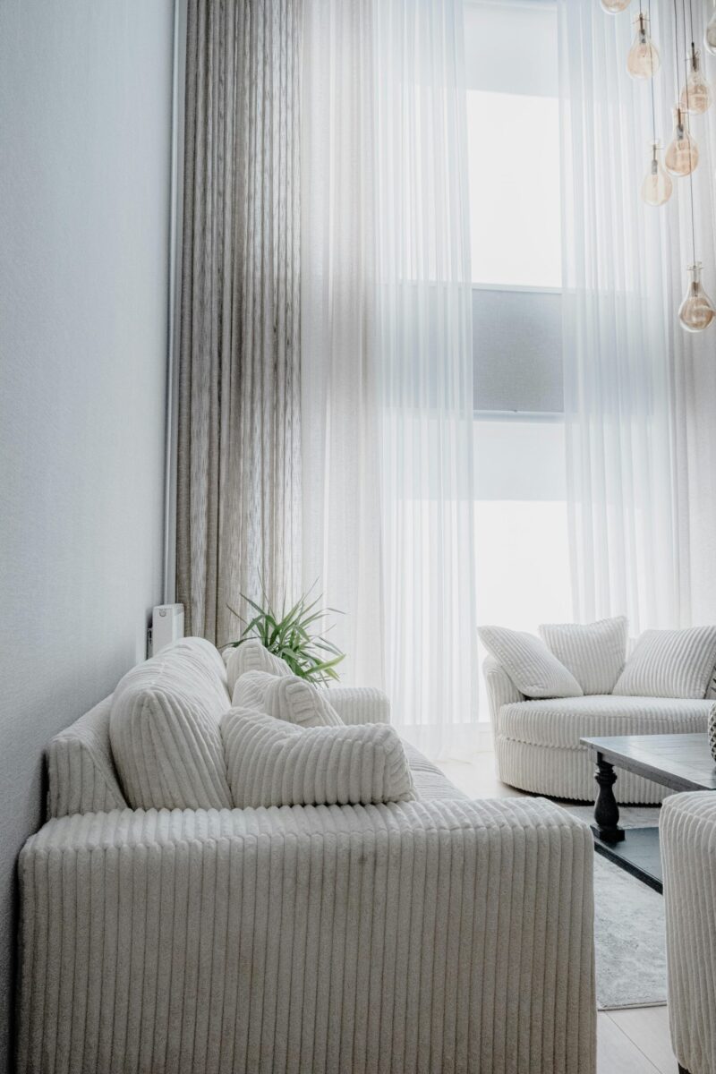 A modern living room with plush seating and tall windows letting in natural light.